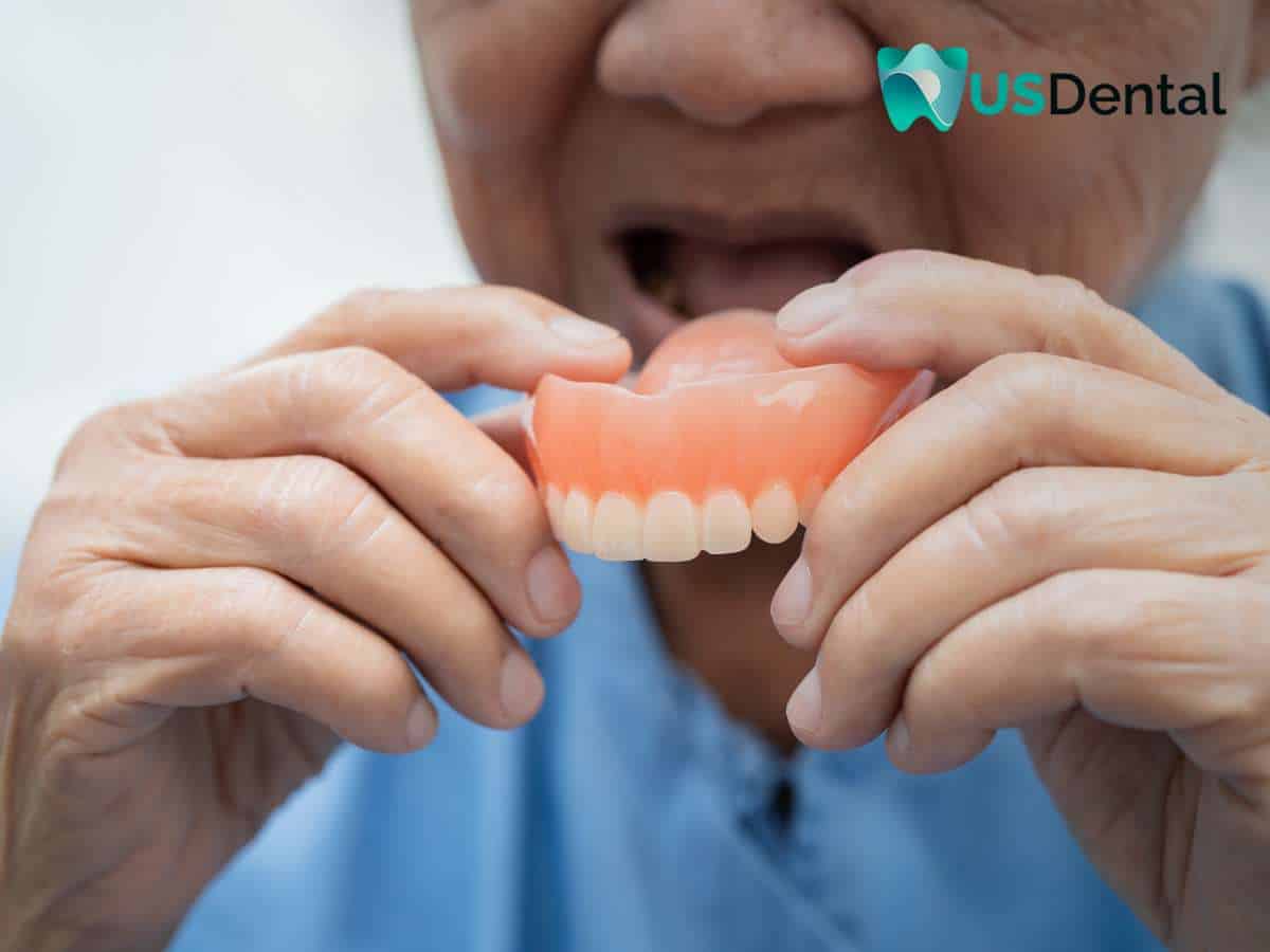 Elderly person holding a denture before wearing it